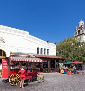 a woman standing next to a red carriage on a street