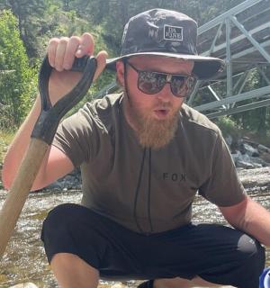 a man in a hat and sunglasses holding a paddle