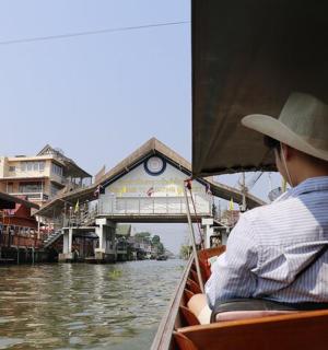 一个戴着帽子的男人乘船沿着运河行驶