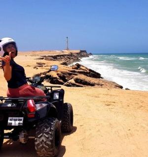 一名男子坐在沙滩上的四轮摩托车上