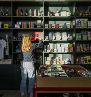 一名女子正在书店里伸手去拿书架