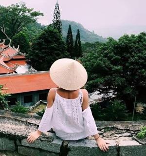 一个戴着帽子坐在墙上的小女孩