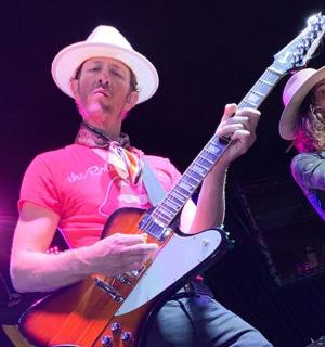 muž a žena hrající na kytaru na pódiu