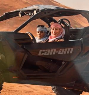 两个人坐在沙漠中的一辆四轮摩托车上