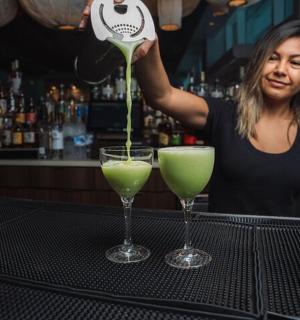 a woman is pouring a drink into two glasses