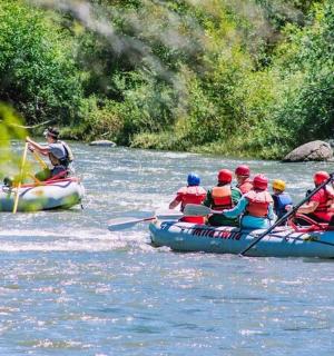 Skupina lidí sjíždí řeku na raftech