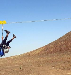 a person hanging on a rope in the desert