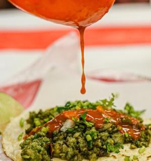 a person drizzling sauce on a plate of food