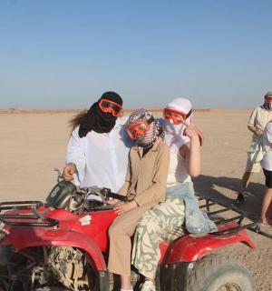 a group of people sitting on a motorcycle in the desert