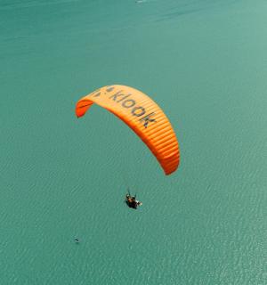 osoba pouštějící draka ve vzduchu nad vodou