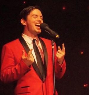 muž v obleku a kravatě mluvící do mikrofonu