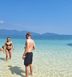 a group of people walking in the water on the beach