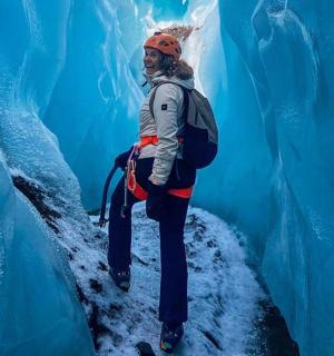 a man is standing in an ice cave with an iceberg