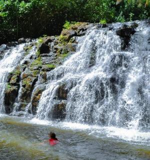 osoba plavající ve vodě poblíž vodopádu