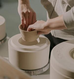 una persona fent un torn de ceràmica sobre una taula