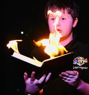 a young man is holding a book with fire on it