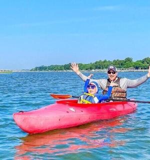 一名妇女和一名儿童在水中的红色皮划艇上