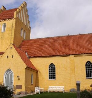 eine gelbe Kirche mit einem hohen Turm mit einem roten Dach