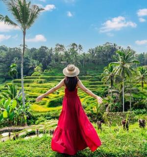 žena u crvenoj haljini gleda rižino polje