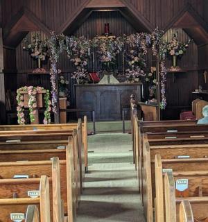 一座空荡荡的教堂,有木制长椅,祭坛上有一位牧师