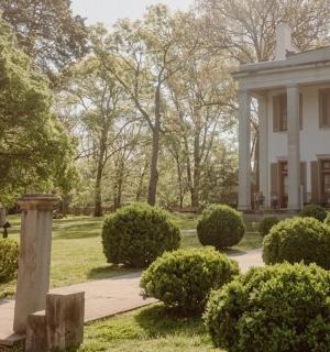 velký bílý dům s keři před ním