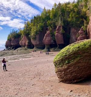一个人在沙滩上行走,旁边有一块大石头
