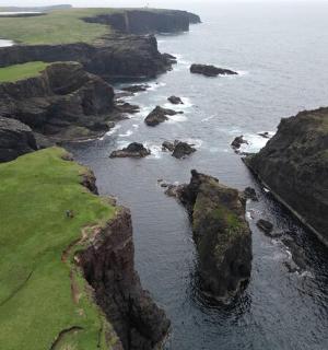 an aerial view of the ocean with rocky coastline