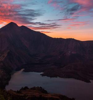 a mountain with a lake in front of a sunset