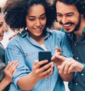 skupina lidí dívajících se na mobilní telefon