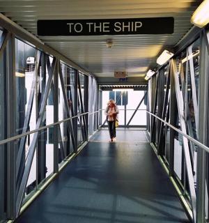 a woman walking down a walkway with a sign that reads to the ship