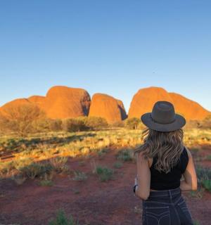 žena v klobouku stojící před klenutými skalami