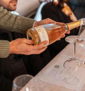 eine Person, die ein Glas Wein auf einen Tisch gießt