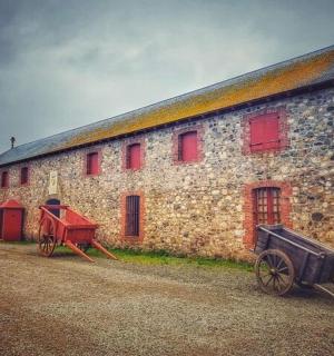 an old stone building with red windows and a red wagon