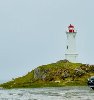 a car parked in front of a lighthouse