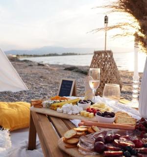 a tray of food and wine on a table near the beach