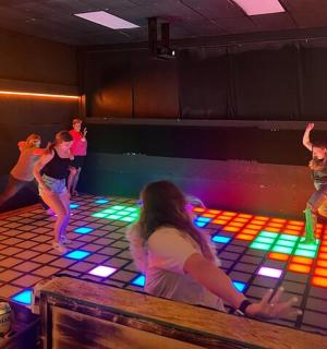 a group of people dancing in a room with lights
