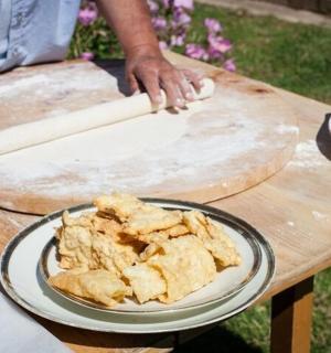 a person rolling out dough on a wooden table with a plate