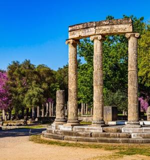 a monument with columns in a park with trees