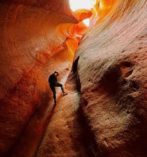 a man is walking through a slot canyon