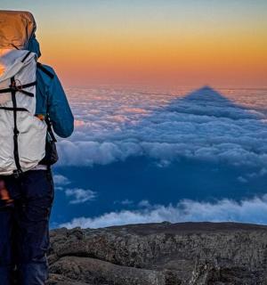 a man with a backpack standing on top of a mountain