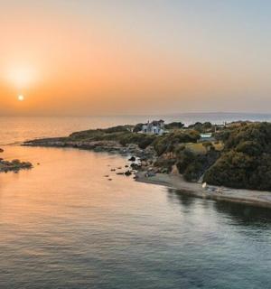 an island in the ocean with the sunset in the background