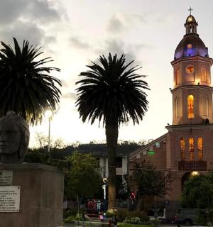 a clock tower with a statue in front of a building