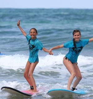 due giovani ragazze che cavalcano tavole da surf nell'oceano