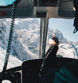 two people sitting in a bus looking out the window at mountains