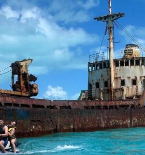 两个人在一艘旧船前骑着水上摩托艇