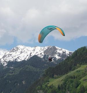 osoba pouštějící draka ve vzduchu nad horou