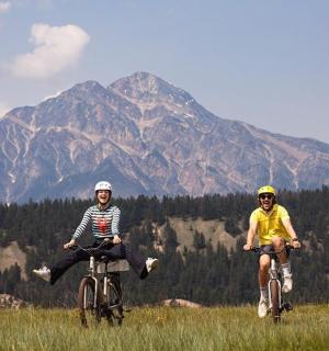 两个人在田野里骑自行车,背景是群山