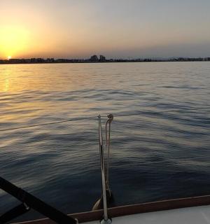 ein Boot im Wasser mit dem Sonnenuntergang im Hintergrund