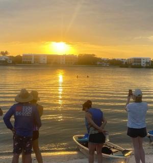 a group of people standing on the beach watching the sunset