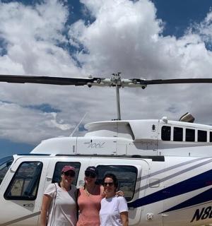 three women standing in front of a helicopter